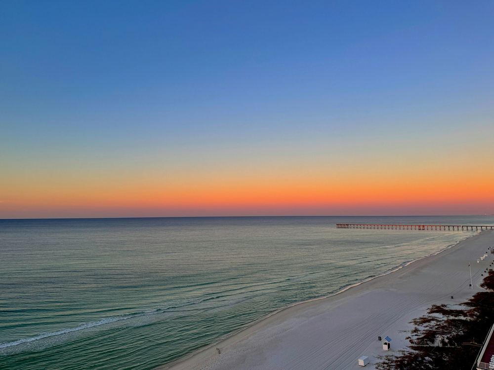 Sunset over the Gulf of Mexico at Panama City Beach, with a fishing pier on the horizon